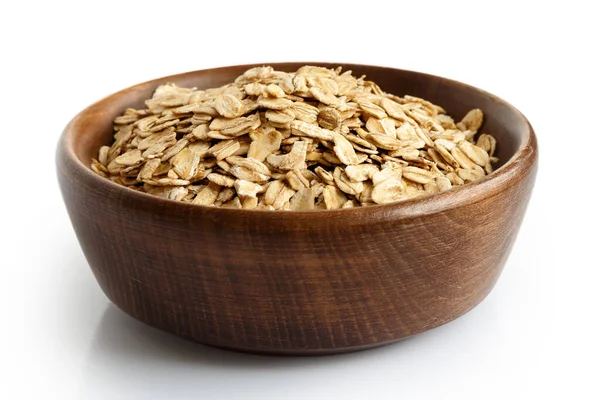 Dry whole porridge oats in dark wooden bowl isolated on white. — Stock Photo, Image