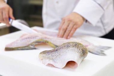 A large zander fish fillet lying on a white chopping board. A ch clipart