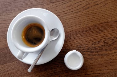 Süt sürahisinin yanında beyaz bardakta klasik İtalyan espresso. 