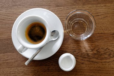 Beyaz bardakta klasik İtalyan espresso, süt sürahisi ve su.