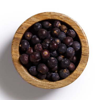 Koyu ahşap kasede kurumuş ardıç meyveleri Aborjin beyazından izole edilmiş.