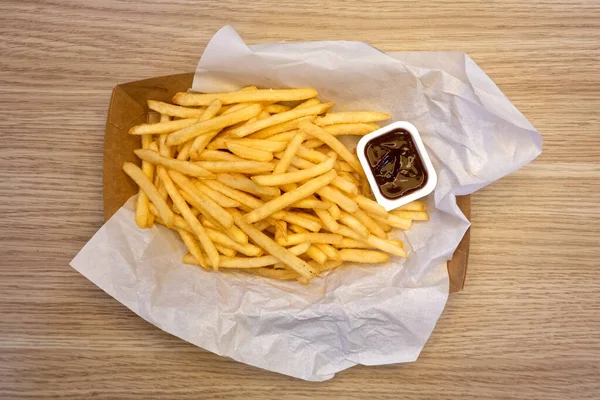 Pommes frites och grillsås på vitt papper på ta bort papper — Stockfoto