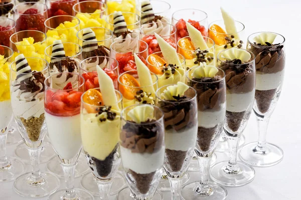 Mixed chocolate and fruit desserts in glass flutes on white. — Stock Photo, Image