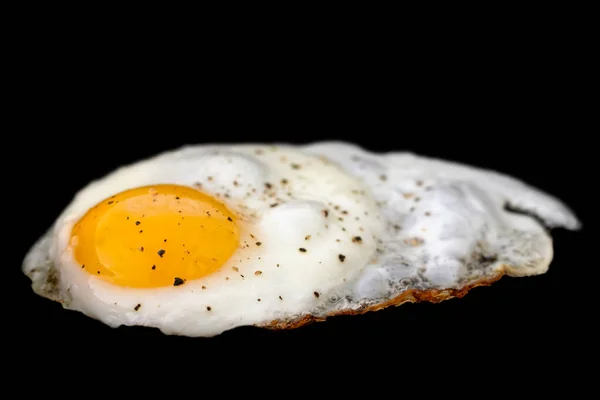 Pojedyncze jajko smażone posypane mielonym czarnym pieprzem izolowanym na — Zdjęcie stockowe