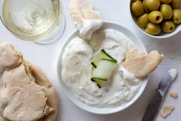 Tzatziki em tigela de cerâmica branca com uma fatia de pepino e uma peça — Fotografia de Stock