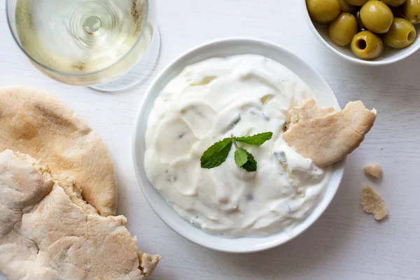 Tzatziki em tigela de cerâmica branca com guarnição de folha de hortelã e um piec — Fotografia de Stock