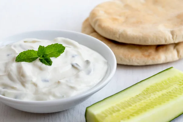 Tzatziki dans un bol en céramique blanche avec garniture de feuilles de menthe à côté de pi — Photo