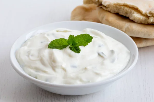 Tzatziki ในชามเซรามิกสีขาวที่มีการตกแต่งใบมินท์ถัดจาก pi — ภาพถ่ายสต็อก