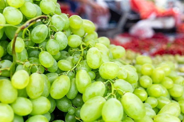 Een hoop groene druiven op de markt. Achtergrond van de wazige markt. — Stockfoto