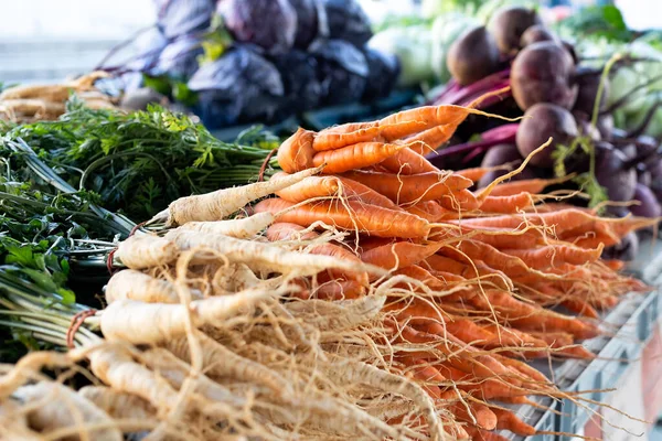 Des grappes de panais et de carottes avec des feuilles au marché. Cacahuètes — Photo