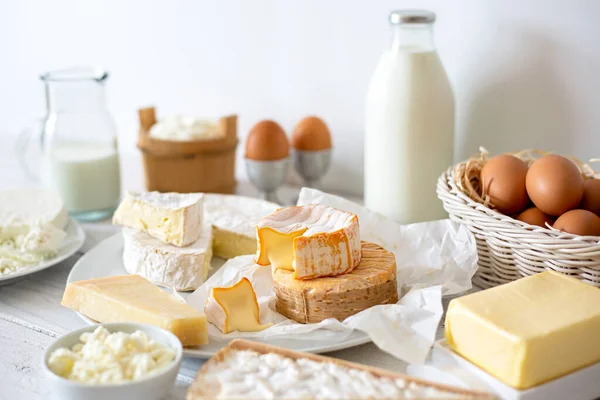 Käse, Milch, Milchprodukte und Eier auf rustikalem, weißem Holzboden — Stockfoto