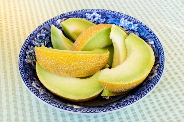 Slices of honeydew melon in a blue antique bowl isolated on gree — ストック写真