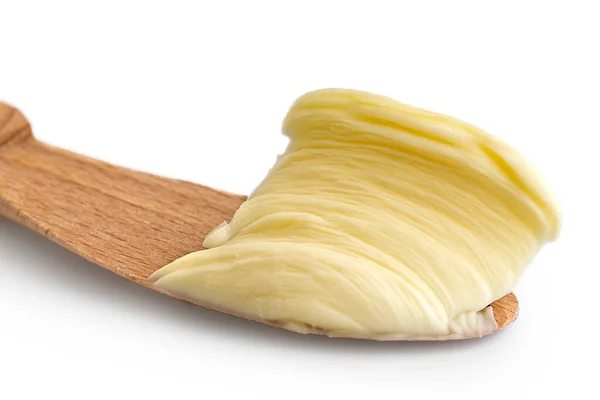 Detalhe da manteiga espalhada na faca de madeira no fundo branco . — Fotografia de Stock