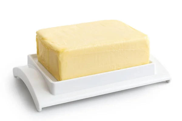Um bloco inteiro de manteiga no prato de manteiga de plástico branco isolado em — Fotografia de Stock