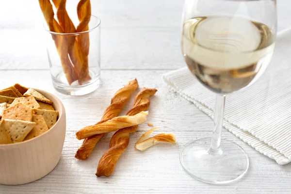 Glass of white wine with party snacks on rustic white wooden tab — Stock Photo, Image