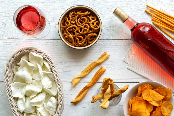 Vin rose avec collations de fête salées sur fond de bois blanc rustique — Photo