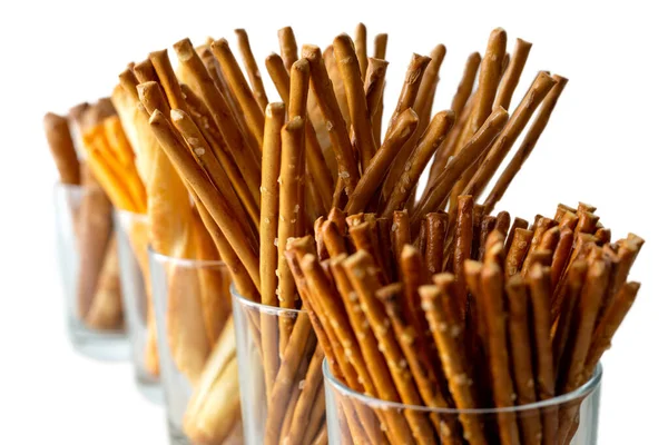 Fila de pretzels, grissini y palitos de queso en vasos en blanco — Foto de Stock