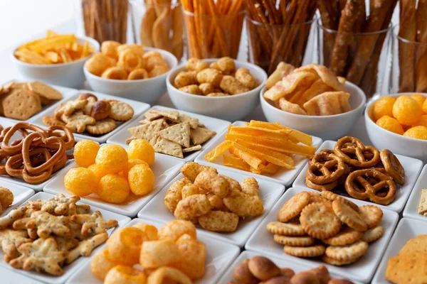 Rangées de nombreux types de collations salées dans des plats en céramique blanche . — Photo