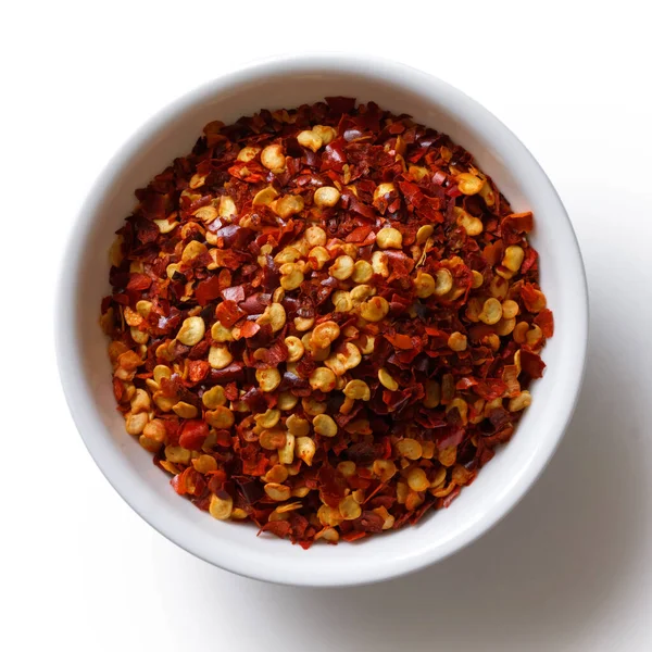 Hrubě mleté chilli papričky v bílé keramické misky izolované na — Stock fotografie