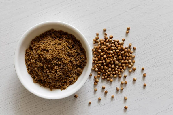 Semillas de cilantro molidas en cuenco de cerámica blanca aisladas en blanco w — Foto de Stock