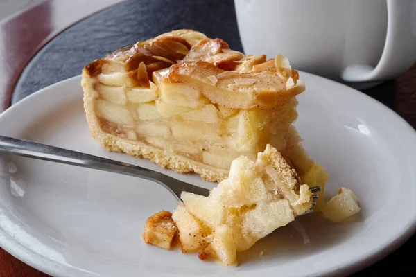 A slice of apple pie with pie on fork on white ceramic plate nex — Stock Photo, Image