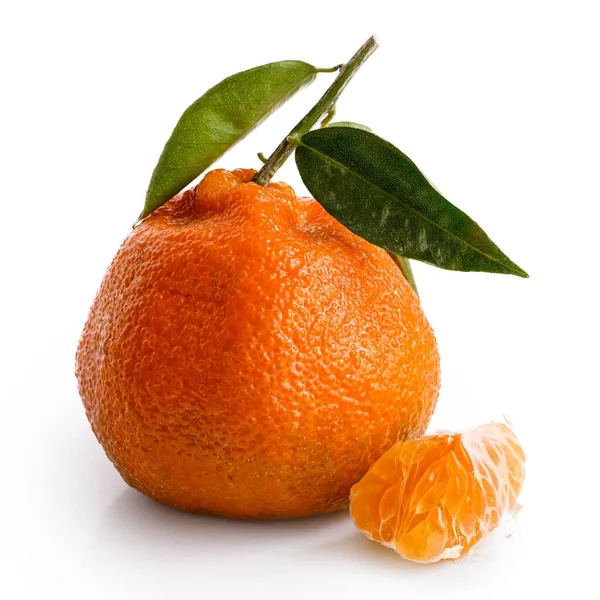 Een gebroken segment van een mandarijn naast hele mandarijn met verlof — Stockfoto