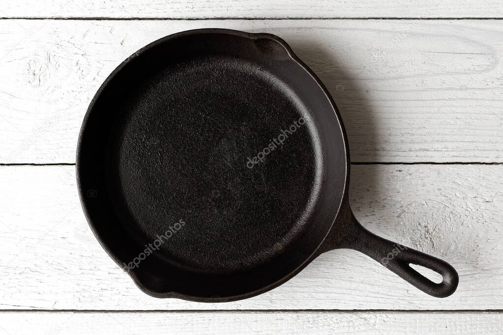 Empty black cast iron pan isolated on white painted wood from ab