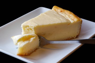 Beyaz seramik tabakta çatallı sade peynirli kek..