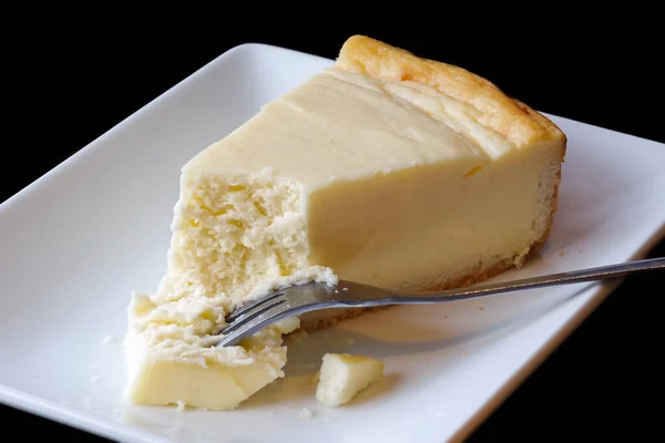 Tavallinen paistettu juustokakku, jossa kakku haarukalla valkoisella keraamisella lautasella . — kuvapankkivalokuva