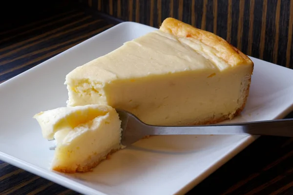 Plain bakad cheesecake med kaka på gaffel på vit keramik platta. — Stockfoto