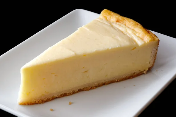 Una rebanada de tarta de queso al horno en un plato de cerámica blanca. Negro —  Fotos de Stock
