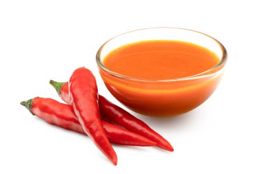 Üç kırmızı biberin yanında cam kasede Peri peri acı biberi sosu
