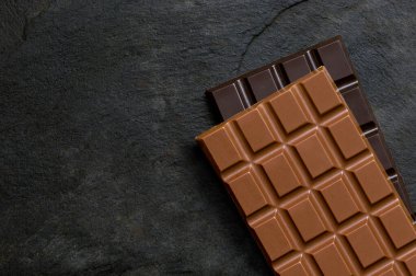 Bir parça sütlü çikolata, bir parça siyah çikolatanın üzerinde.