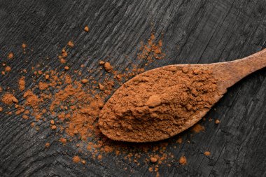 Tahta bir kaşıkta kakao tozu siyah bir tahta boa 'da izole edilmiş.