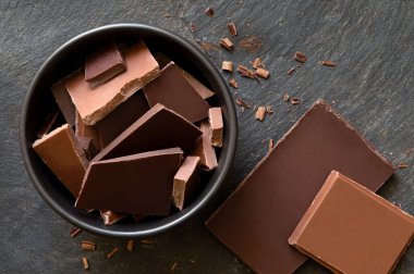 Siyah seramik kasede koyu ve sütlü çikolata parçaları izole edilmiş.