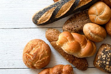 Beyaz boyalı ahşap üzerinde baget ve ekmek ruloları karıştırdım. Üst görünüm.