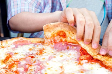 Bir dilim pizza alan bir çocuk..