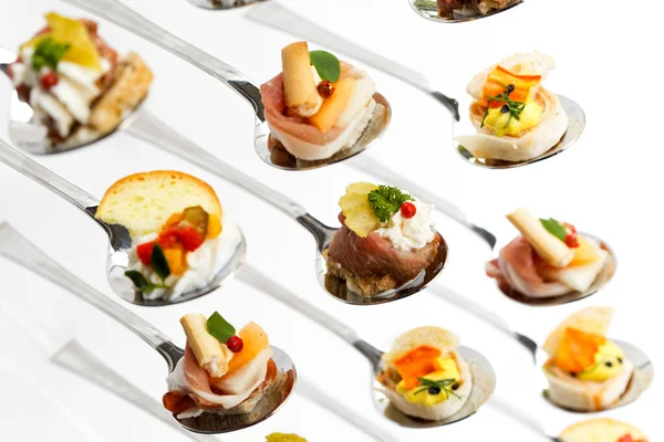 Closeup of mixed canapes on metal spoons. White background. — Stock Photo, Image