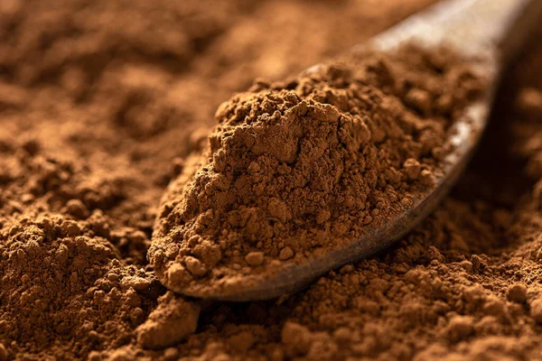 Dettaglio di cacao in polvere su un cucchiaio di legno seduto su cacao in polvere — Foto Stock