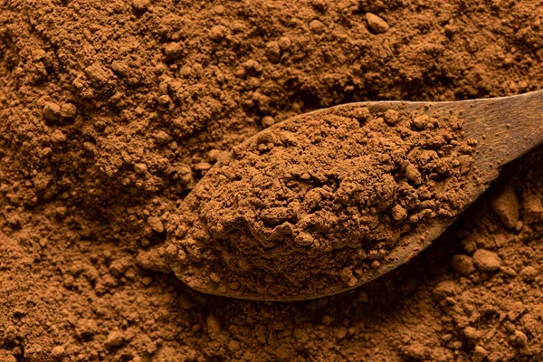 Dettaglio di cacao in polvere su un cucchiaio di legno seduto su cacao in polvere — Foto Stock