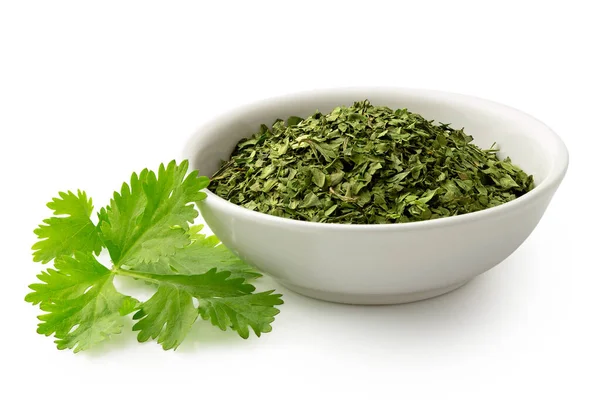 Dried chopped coriander leaves in white ceramic bowl next to fre — Stock Photo, Image