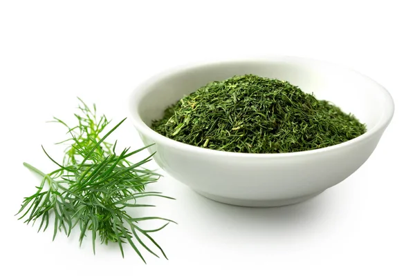 Dried chopped dill in white ceramic bowl next to fresh dill leav — Stock Photo, Image