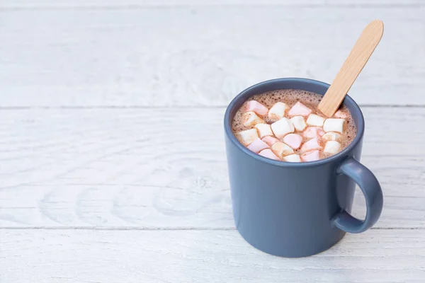 Hot chocolate with small marshmallows and wooden stirrer in a bl