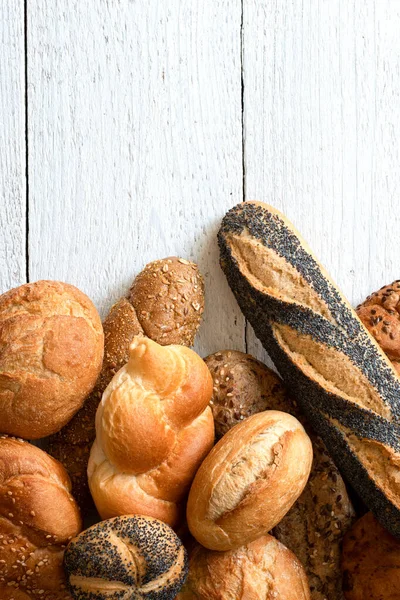 Baguettes mixtos y panecillos sobre madera pintada de blanco. Vista superior . — Foto de Stock