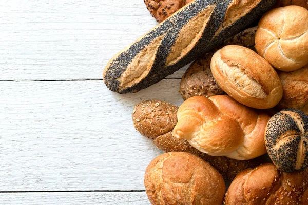 Gemengde stokbrood en broodjes op wit geschilderd hout. Bovenaanzicht. — Stockfoto