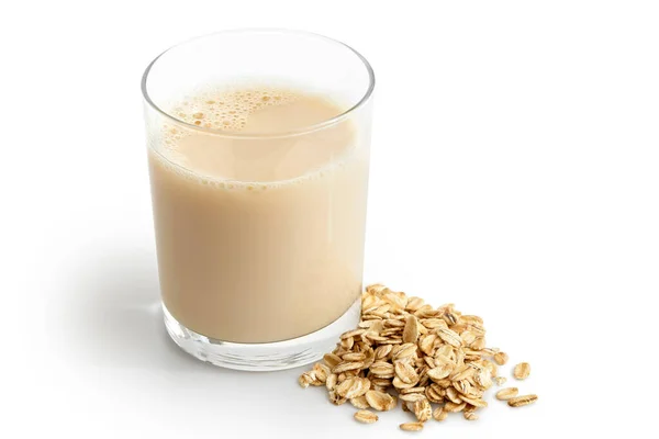 Vaso de bebida de avena junto a una pila de avena seca aislada en blanco — Foto de Stock