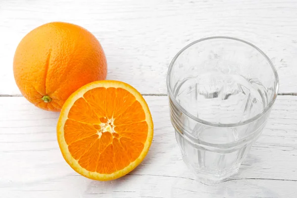 Bir bütün ve portakalın yarısını boş bir bardağın yanına kes. — Stok fotoğraf