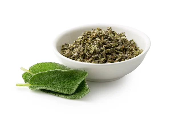 Dried rubbed sage in a white ceramic bowl next to fresh sage lea — Stock Photo, Image