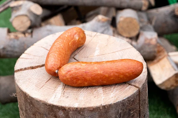 Dos salchichas europeas sobre un tronco redondo de madera frente a un pil —  Fotos de Stock