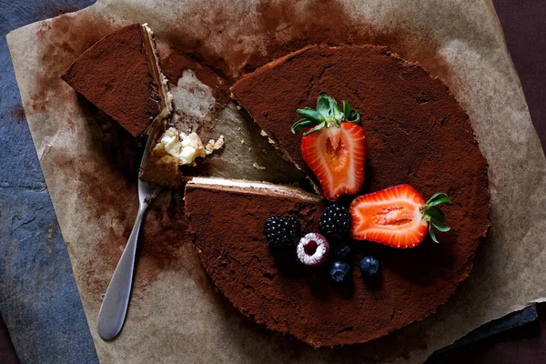 Closeup of whole homemade cheesecake on baking paper with cocoa — Stock Photo, Image